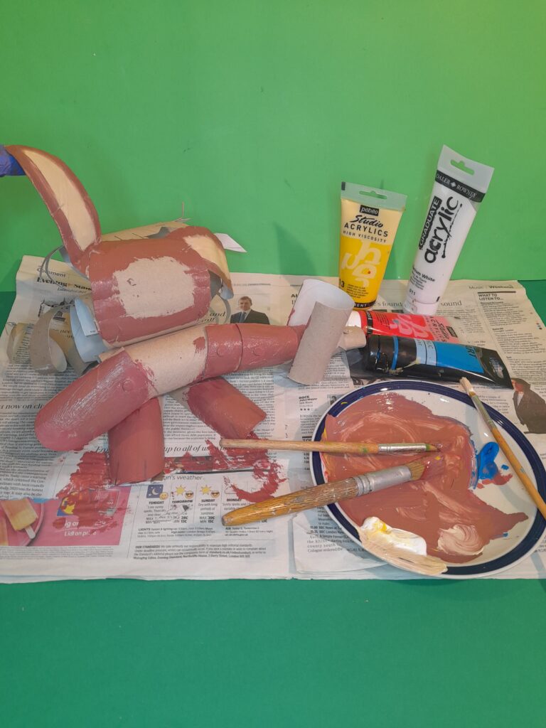 21) Make up brown with red, yellow and blue a little at a time, add white to lighten colour. Leave some space for the face. Paint the hammer red and the vest in blue, paint  cream inside the ears.
