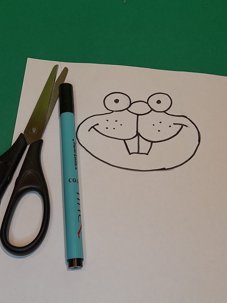 24) Draw cartoon face of a bunny onto the white paper cut out and with glue stick onto face area.
