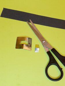 12) Fold gold square in half and cut out a smaller square and glue onto the middle of black strip.