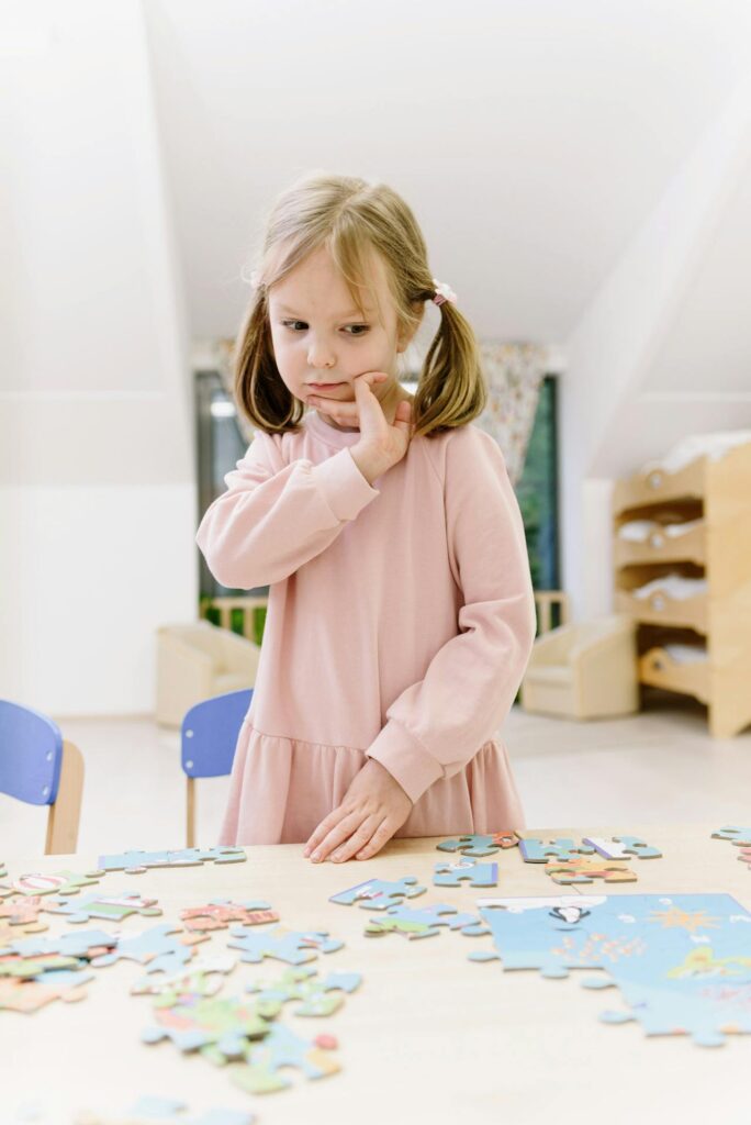 Girl thinking over her puzzle. Picture from Pexels.com by Ksenia Chernaya.