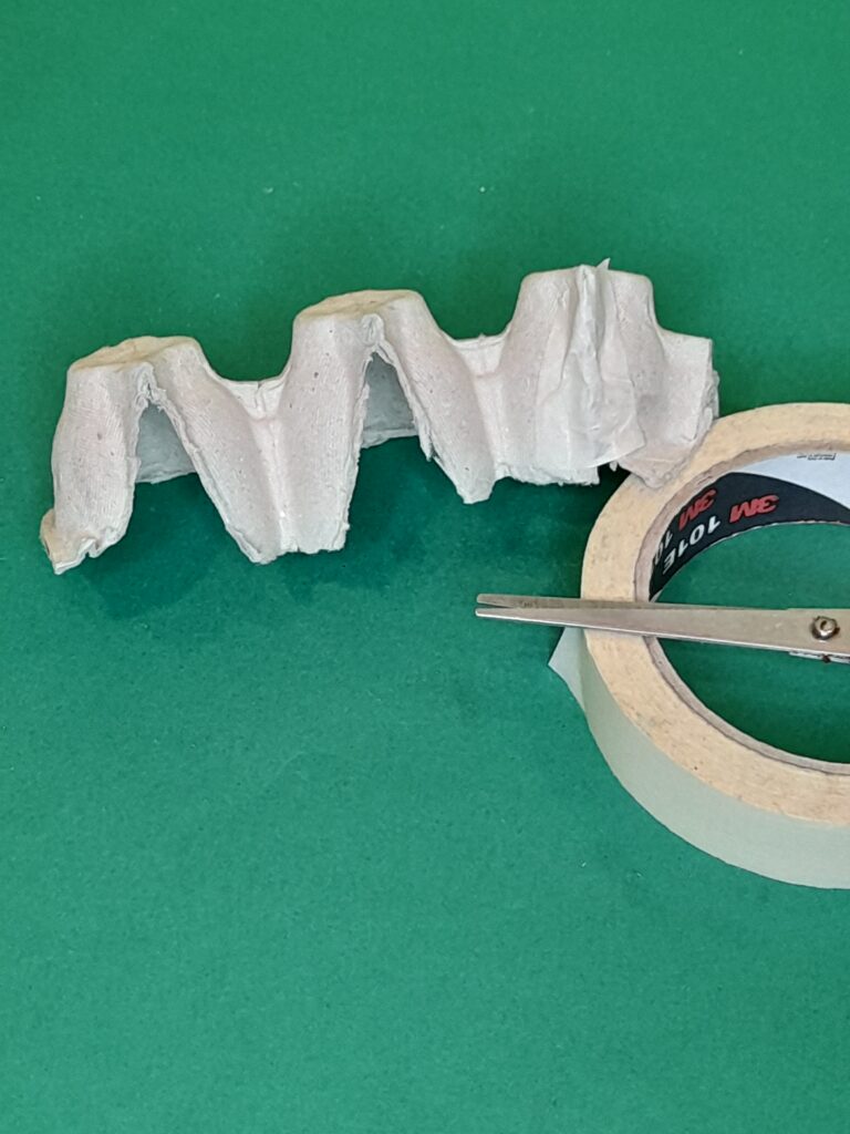 1) Cut a long strip of three egg cups, from an egg carton.