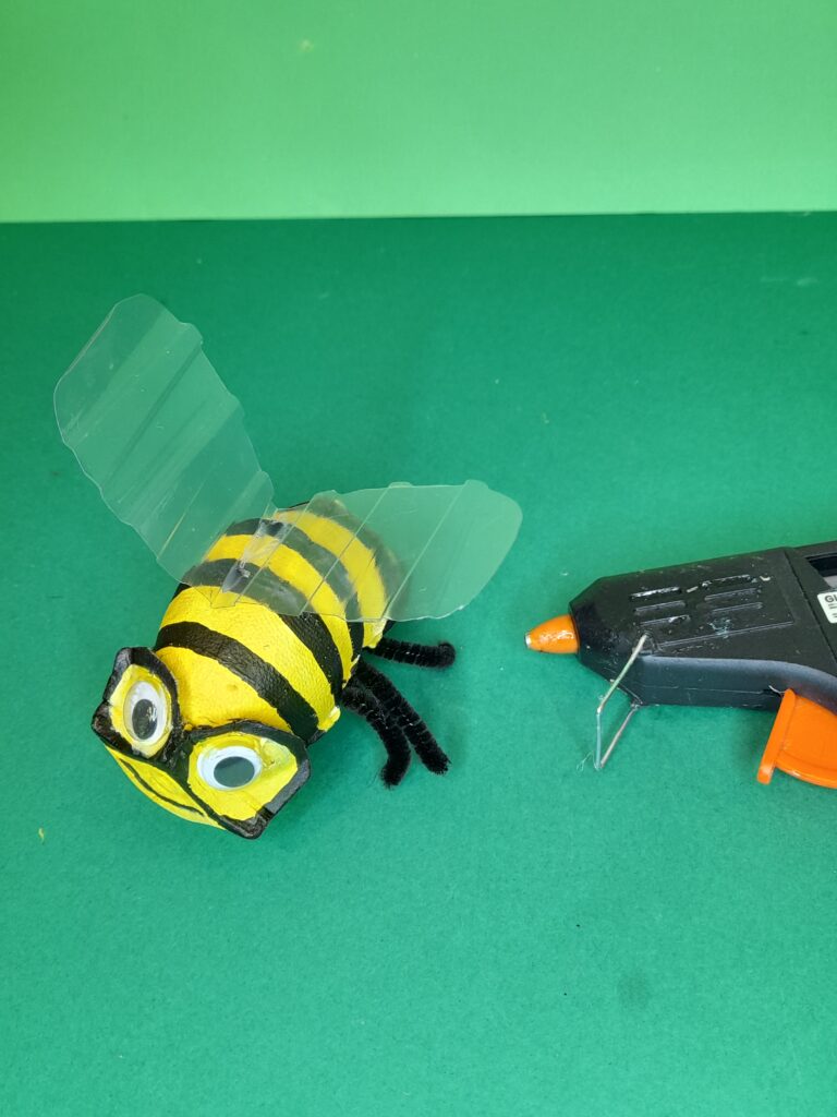 9) Paint black lines across the bee, and around the eyes to form goggles, drawn a smiley mouth, then hot glue on the wings on the bees back.