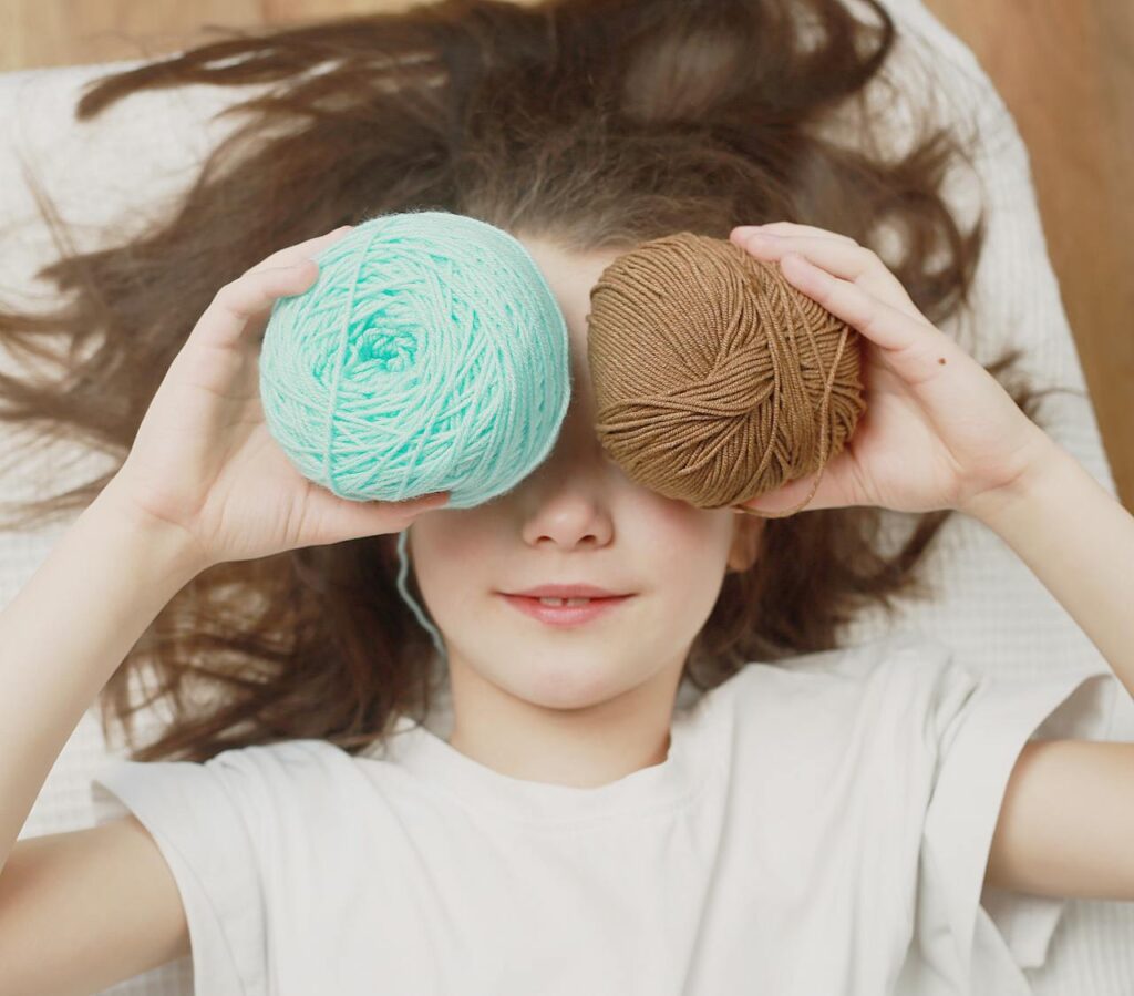 Girl with 2 balls of wool. A Pexels picture.