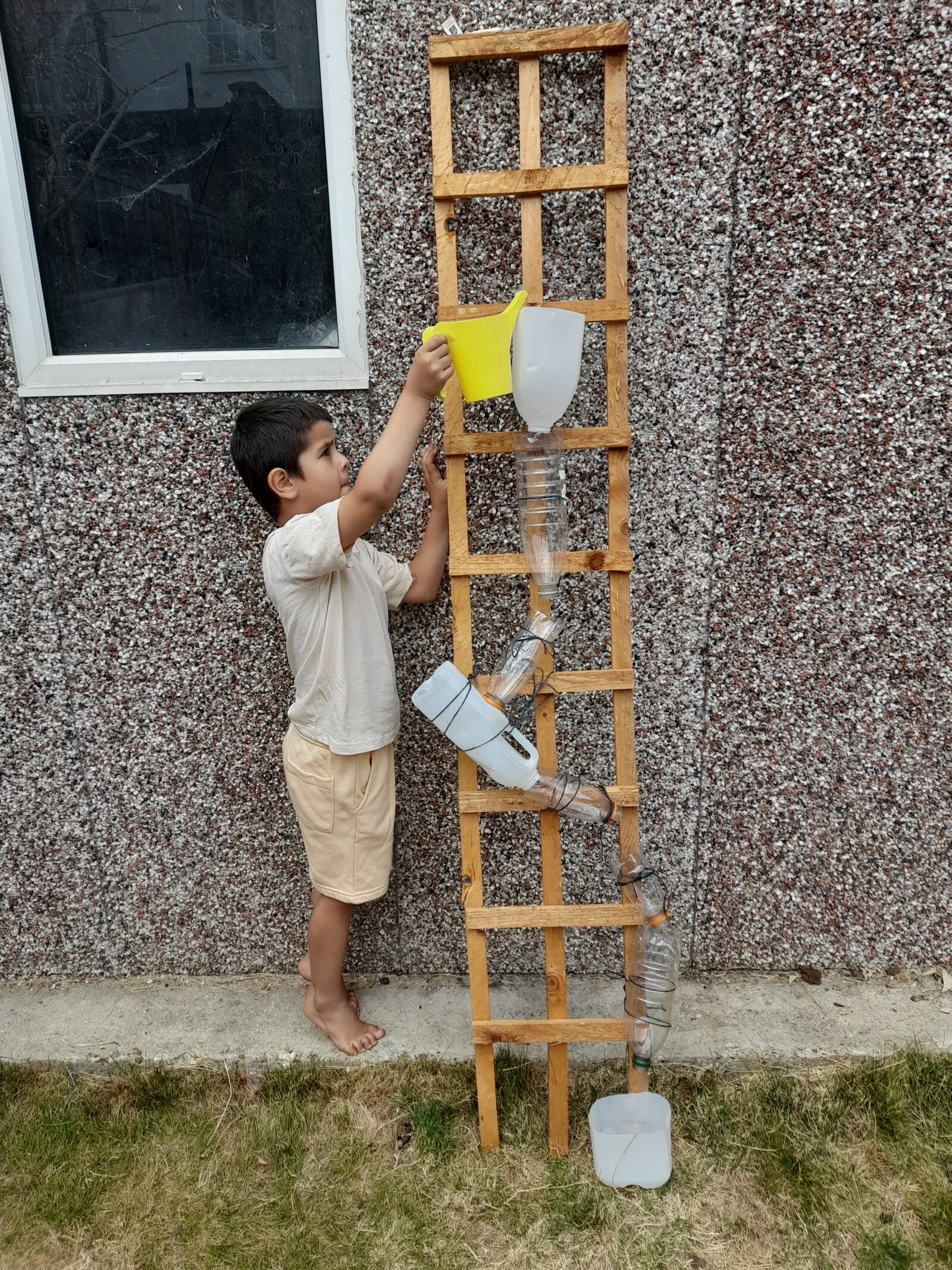 A child playing with a DIY plastic bottle water wall